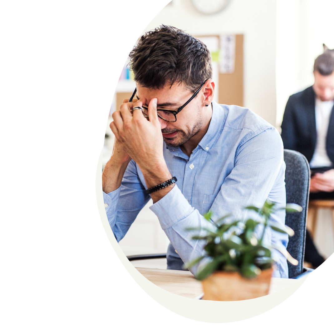 Man hunched over table with hand touching forward in stress
